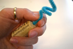 hand holding cork with pipe cleaner in it