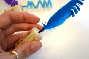 hand holding cork with feather in it