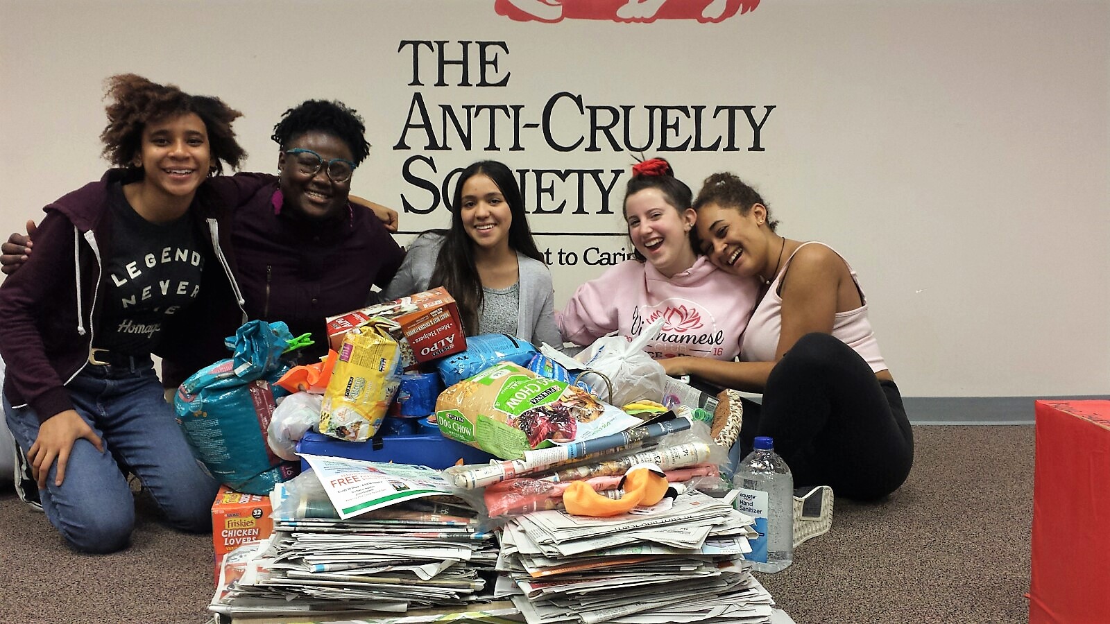 Group of students around donation of newspapers and pet food
