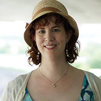 Woman in brown straw hat with brown hair wearing a blue dress