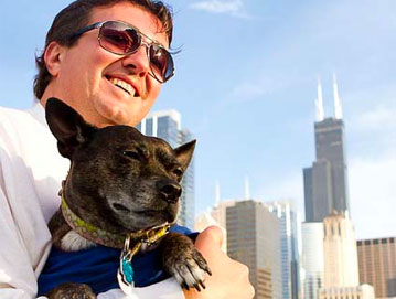Man with sunglasses holding dark colored dog on cruise down the Chicago River