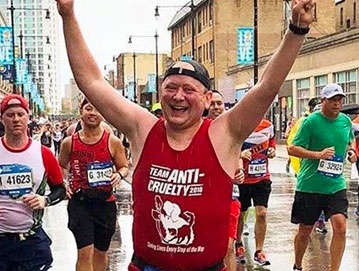 Man in red Team Anti-Cruelty jersey running the Chicago Marathon