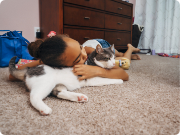 Little girl resting curl up with her cat on her bedroom floor. 