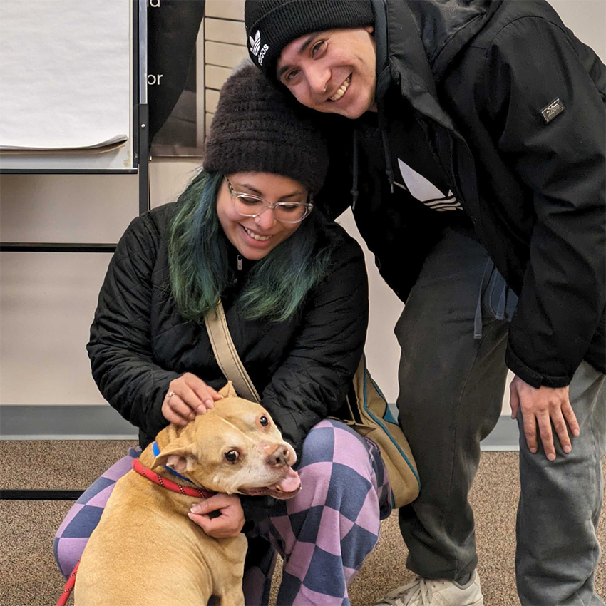 Two young people with a medium sized friendly dog