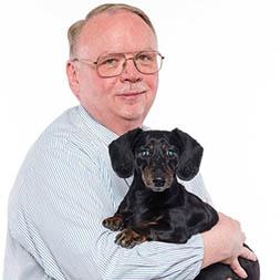 Man in blue shirt holding small black dog