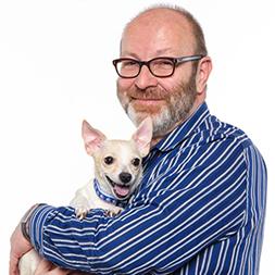 Man in blue and white striped shirt smiling holding small dog