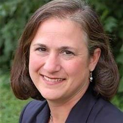 Woman with short brown hair in a blue blazer smiling