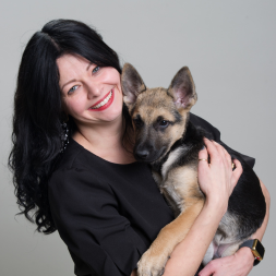 Woman with black hair holding a small dog.