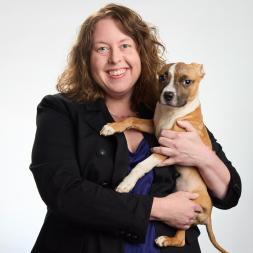 A woman with brown hair holding a brown and white puppy