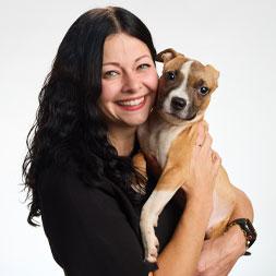 Woman with black hair holding a small dog.