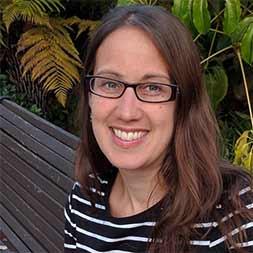 A happy woman with glasses sitting on a bench