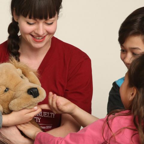 Woman surrounded by kids playing with puppet dog